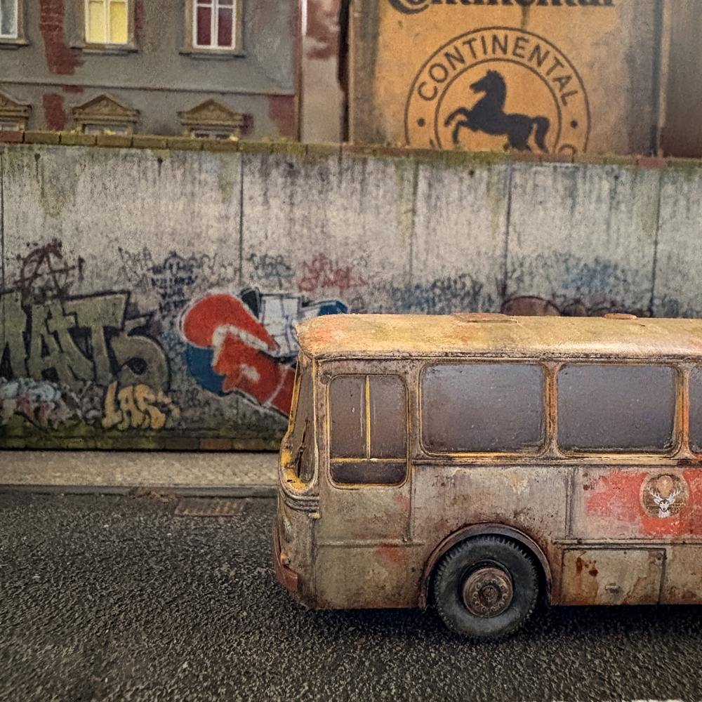 H0-Diorama Alter Jägermeister Bus vor einer gealterten Betonwand mit Graffiti, Tags, Schmutzspuren und verwittertem Gehweg.